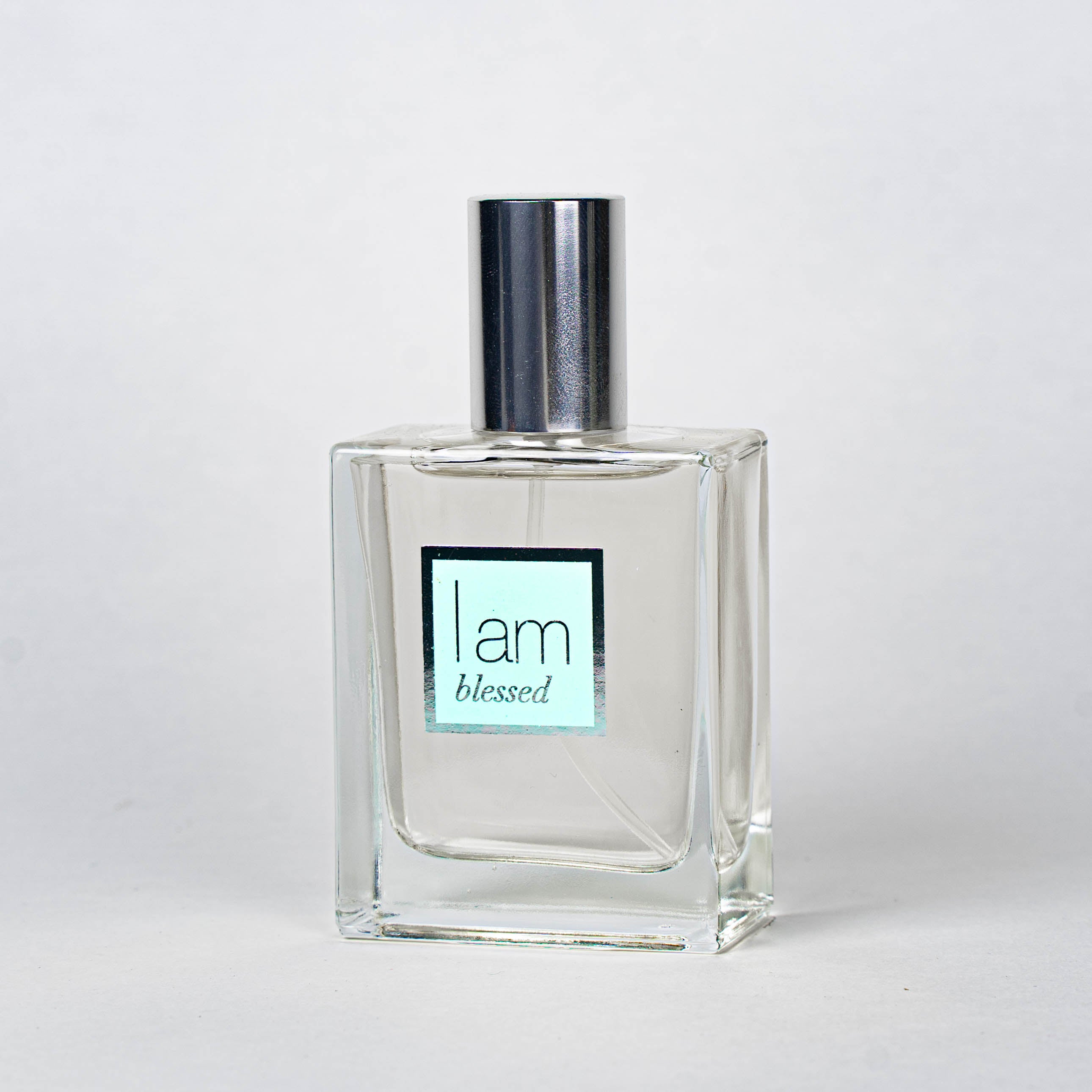 Clear perfume bottle with silver cap on a light gray background