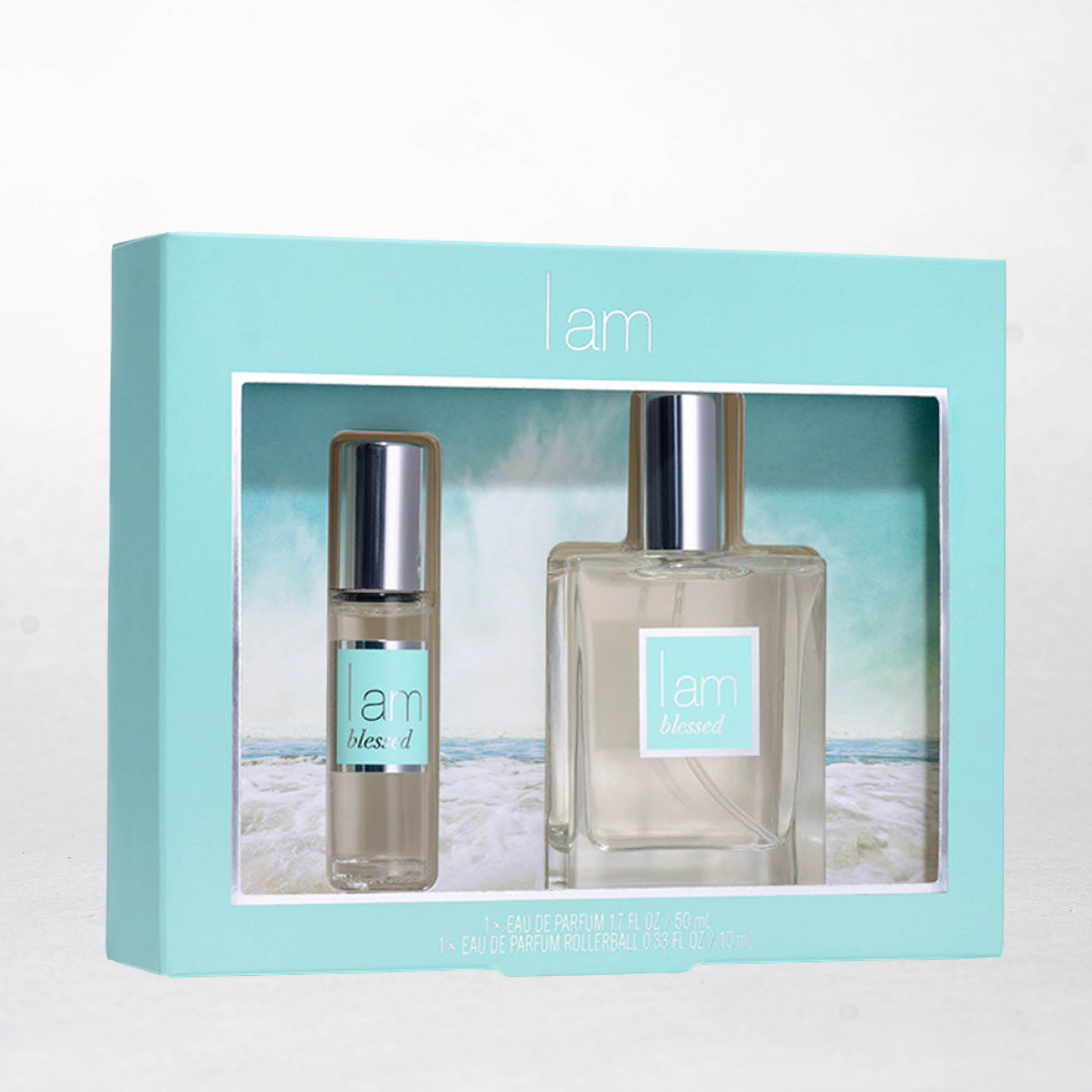Two perfume bottles in a box with 'i am' branding on a beach background
