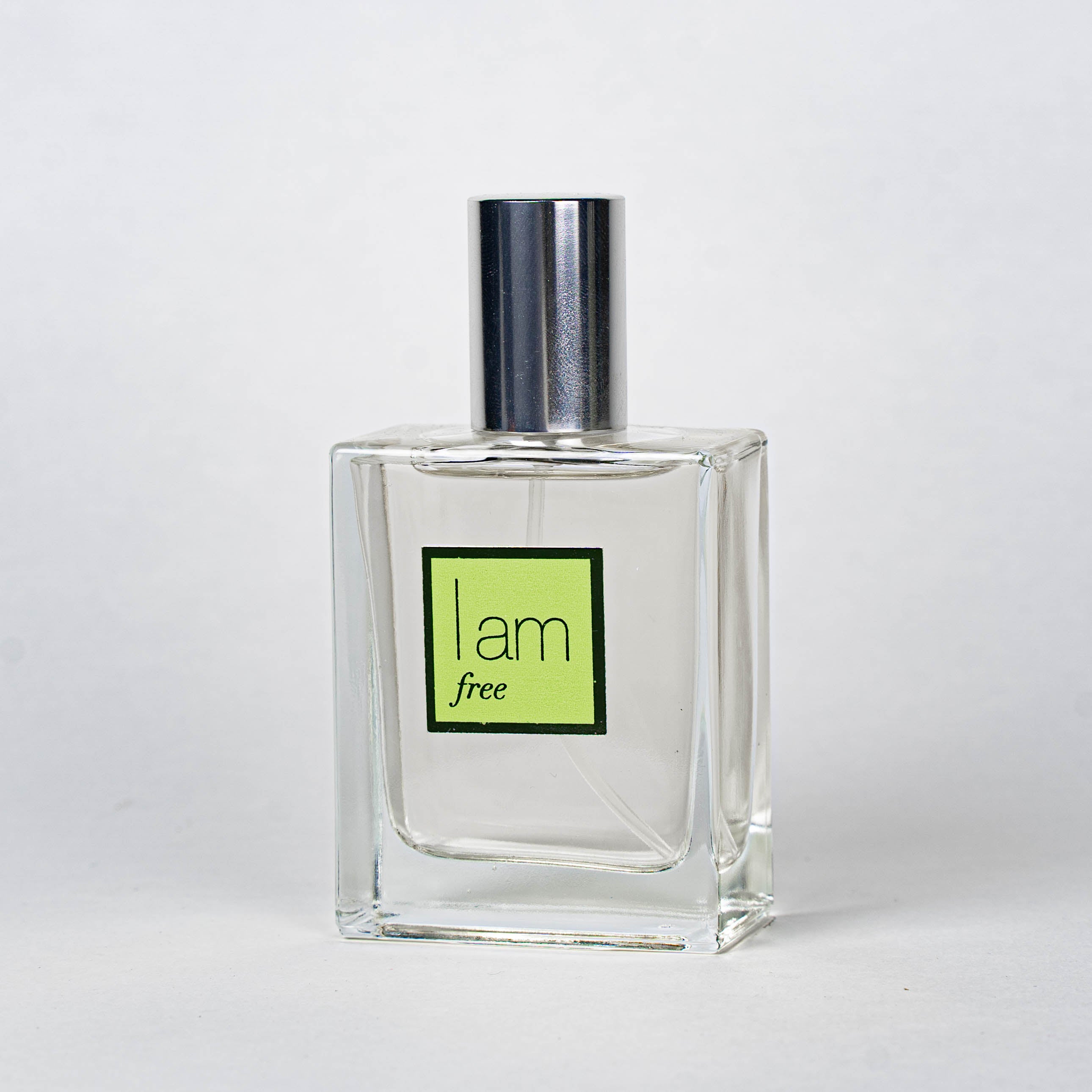 Clear perfume bottle with a silver cap and green label on a white background